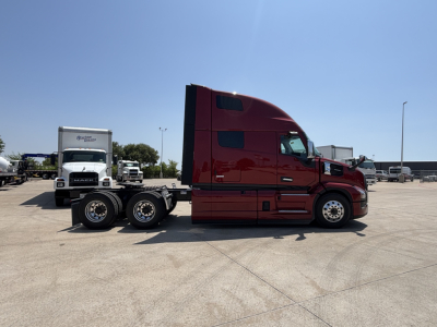 Side view of a red Mack PR64T76H truck tractor showing a 6x4 tractor unit with sleeper cab in a dealership lot.