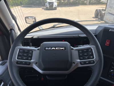 Mack PR64T76H truck interior showing steering wheel with Mack logo and control buttons on both sides.