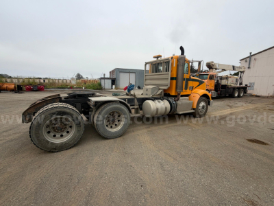Peterbilt 367 truck tractor side view showing chassis rear dual wheels and fuel tanks in an industrial yard.