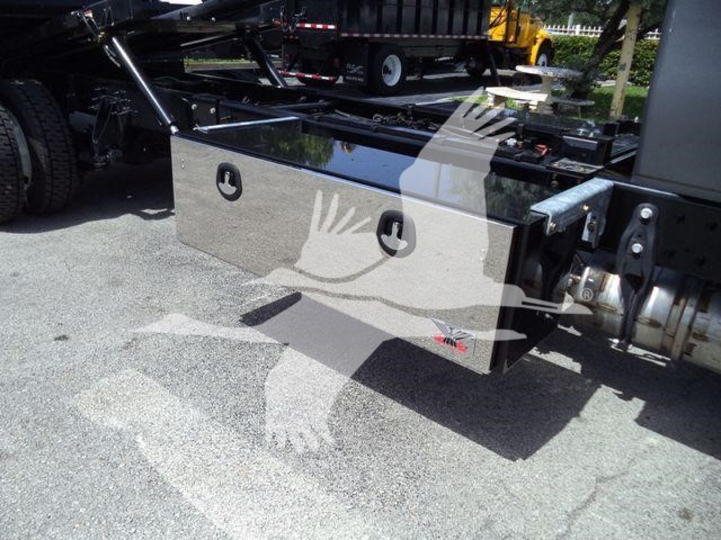 Aluminum toolbox mounted on truck chassis with handles and pad in view.