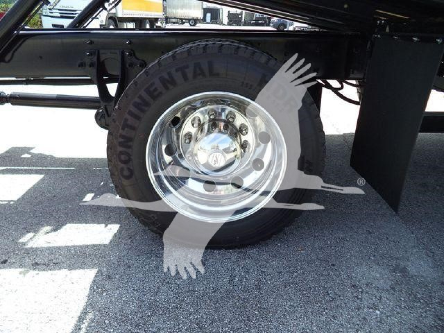 Wheel and tire of a truck showing a polished steel rim and Continental brand tire, undercarriage components and suspension visible.