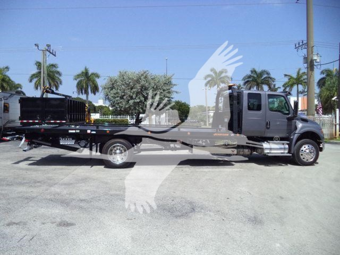 International MV rollback truck showing flatbed with cab in profile and branding on door.
