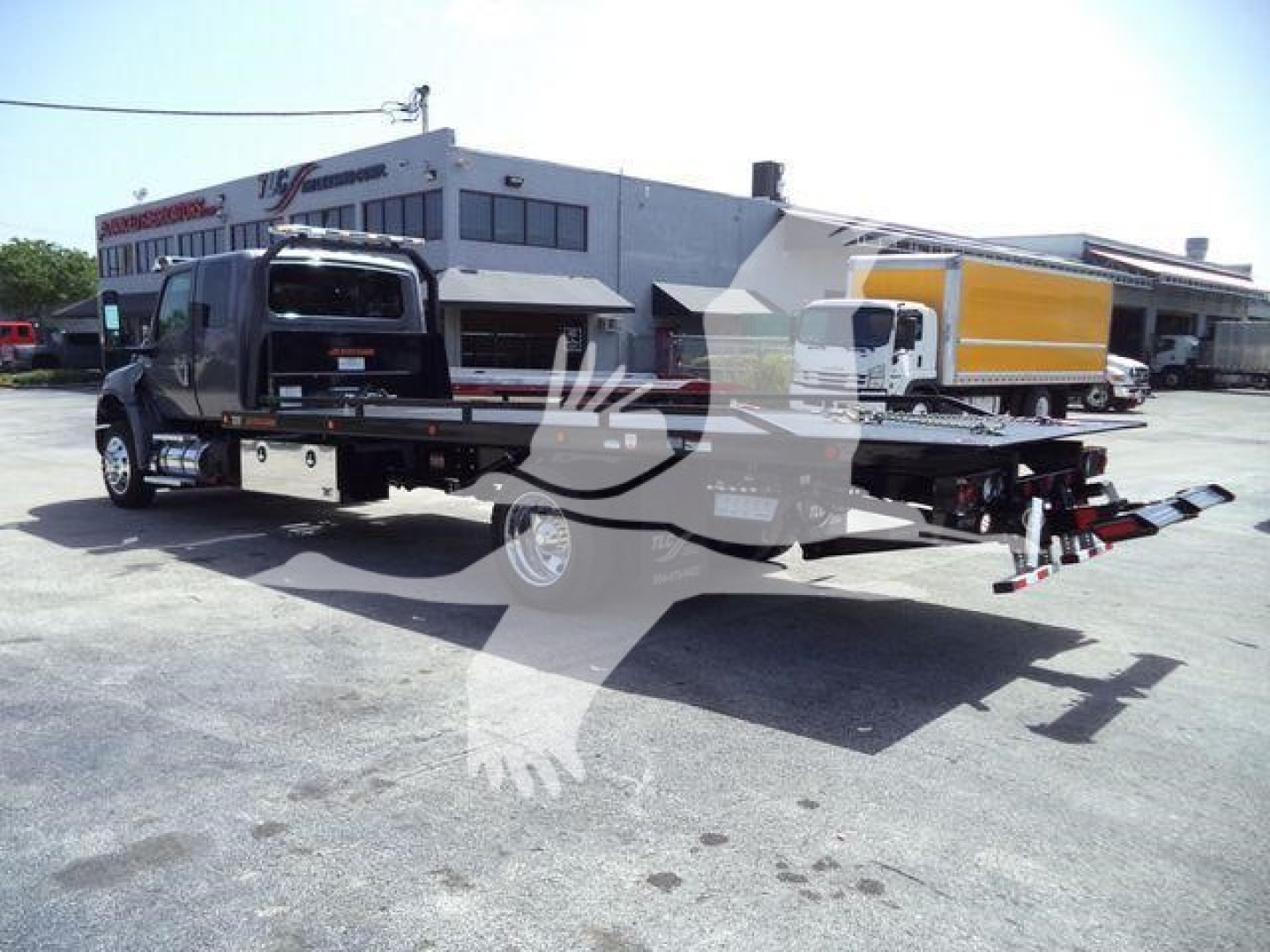 Truck with rollback equipment showing flatbed and tow apparatus, International MV 2027 branding not visible in photo.