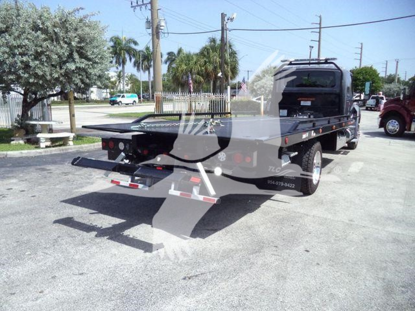 Tow truck flatbed with rear equipment and taillights visible; no legible labels or model text clearly readable from this angle.