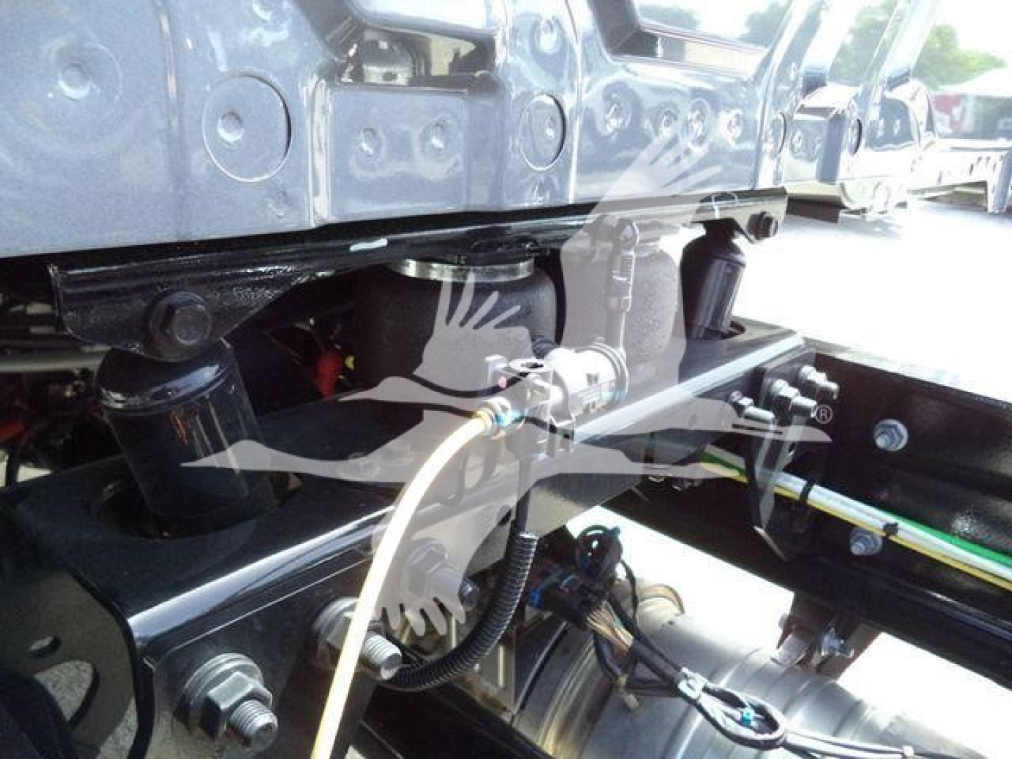 Truck chassis showing hydraulic lines and drivetrain components under the cab, International MV rollback truck. 