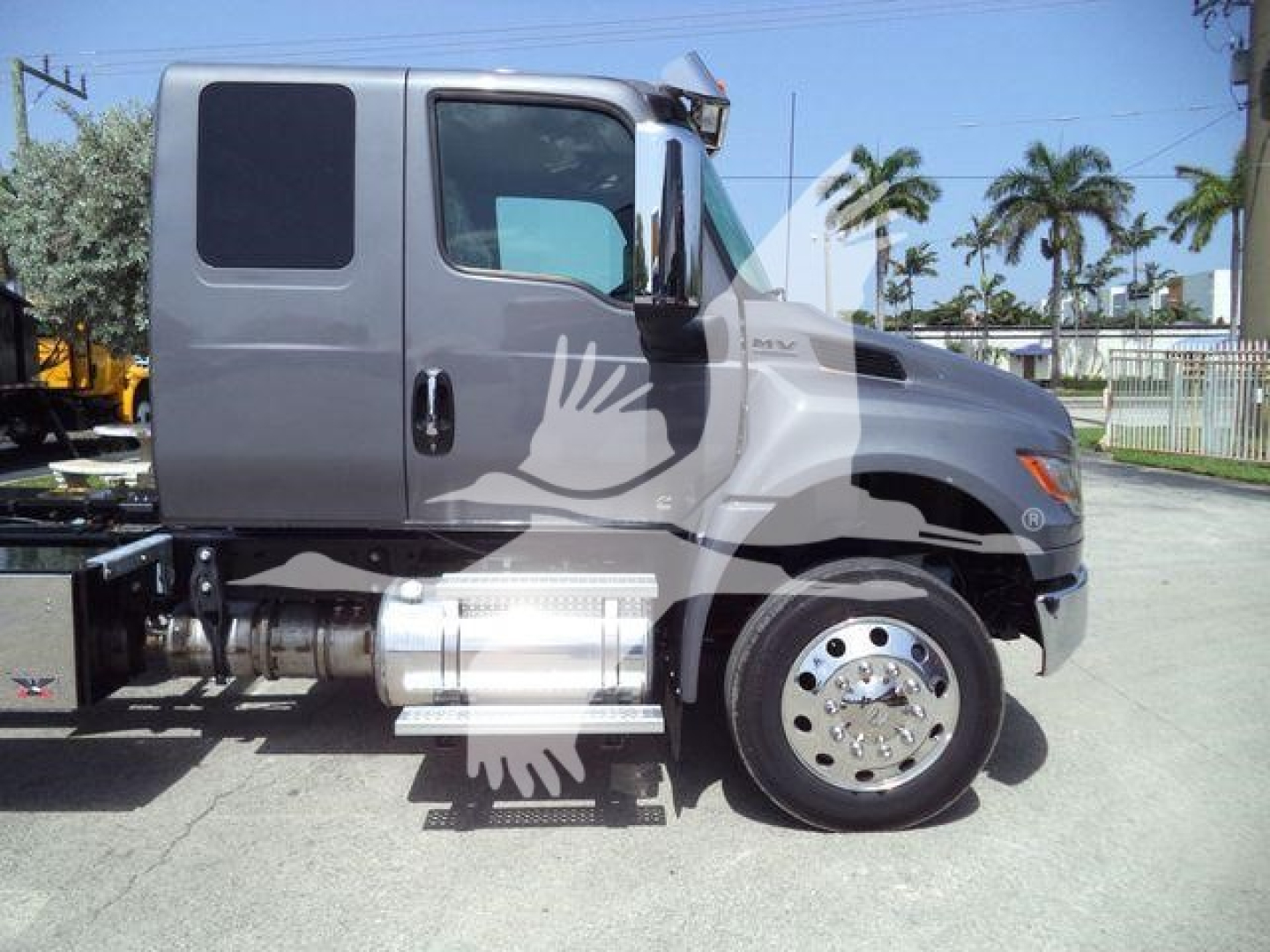 Truck cab side view showing International MV rollover with dual rear wheels and chrome fuel tanks; VIN label not visible.