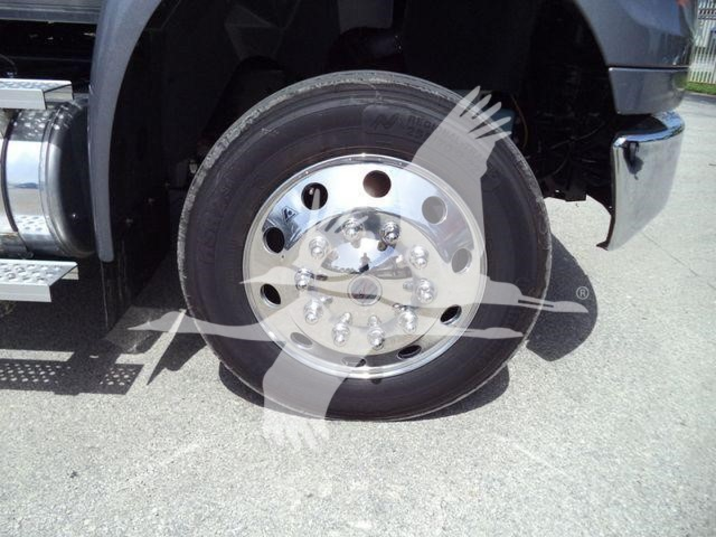 Truck wheel showing polished chrome rim and tire with aluminum fuel tank step and fender in view.