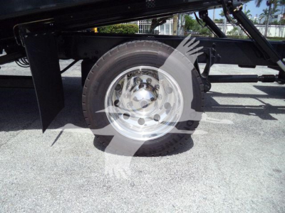 Truck wheel assembly with dual-axle setup and polished steel rim; undercarriage frame and hydraulic components visible.
