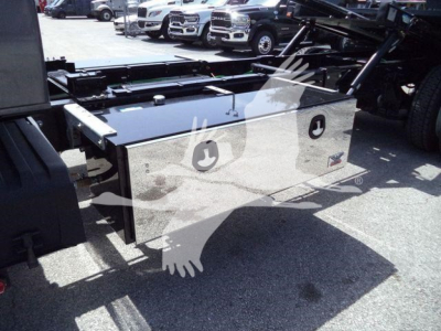 Aluminum toolbox mounted on a rollback truck chassis with polished silver surface and two circular recessed handles visible.