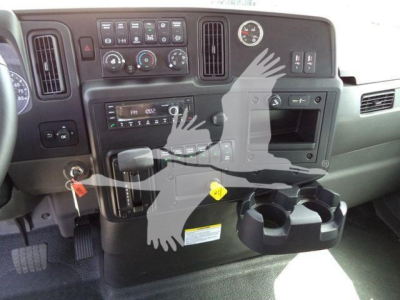 Dashboard and cupholders of a 2027 International MV rollback truck showing center controls and steering column area.