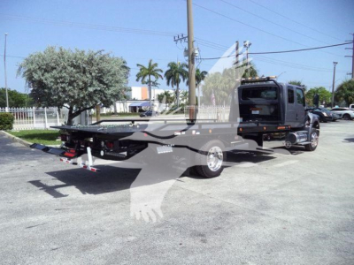 Tow truck with black cab and flatbed trailer in a parking lot, VIN 1HTEUMML0VS478861 visible on listing