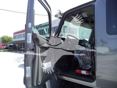 Interior of a new International MV rollback truck cab with open door showing steering wheel and dashboard.