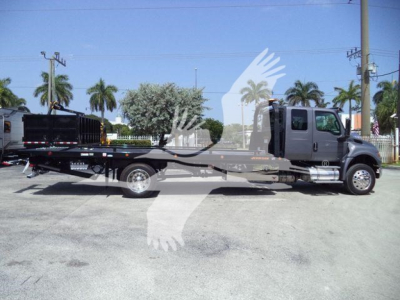 International MV rollback truck showing flatbed with cab in profile and branding on door.