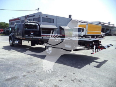 Truck with rollback equipment showing flatbed and tow apparatus, International MV 2027 branding not visible in photo.