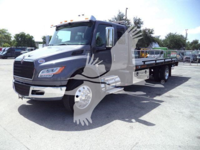 International MV rollback truck in a parking lot with flatbed, front grille, and side mirrors visible.