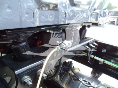 Truck chassis showing hydraulic lines and drivetrain components under the cab, International MV rollback truck. 