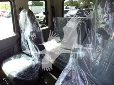 Truck interior showing front passenger and rear seats wrapped in plastic protective covers in a new International MV rollback truck.