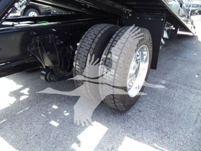 Truck rear dual wheels and undercarriage with suspension and frame visible in a parking lot.