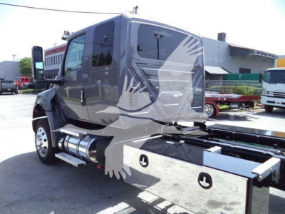 Truck cab of a 2027 International MV rollback truck with chrome fuel tanks and a metal toolbox in the side, showing rugged body lines and a gray exterior.