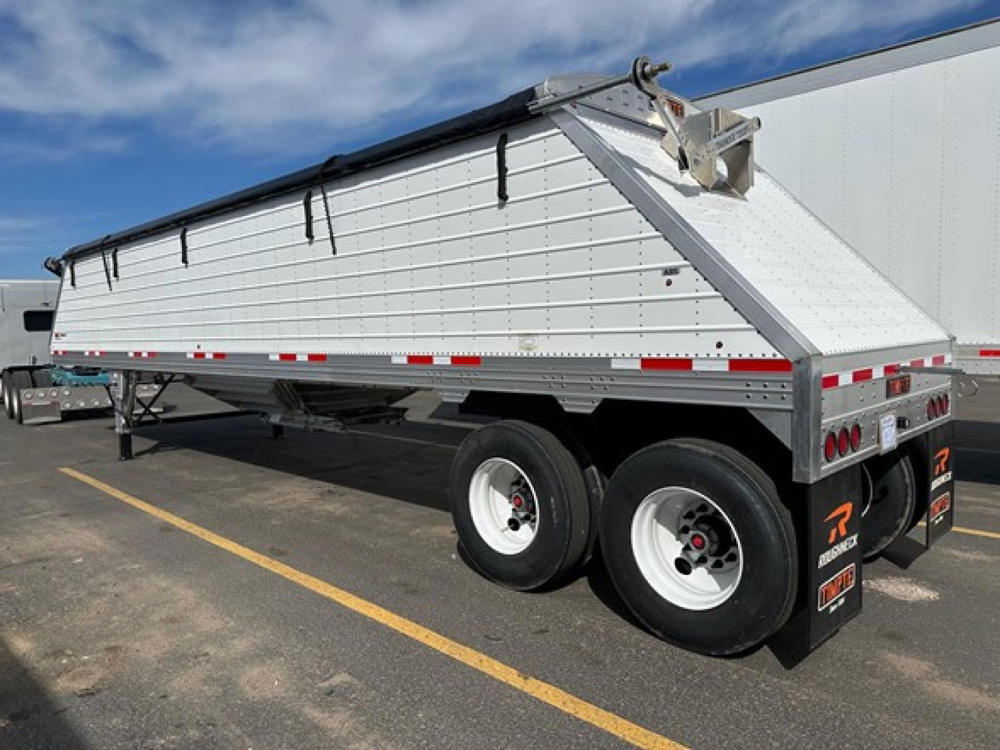 Frac sand hopper trailer showing Timpte brand with silver side walls and dual axles in a parking lot.