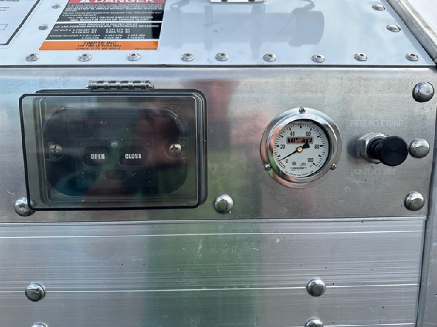Timpte frac sand hopper trailer control panel showing open/close switch and pressure gauge with metal housing.