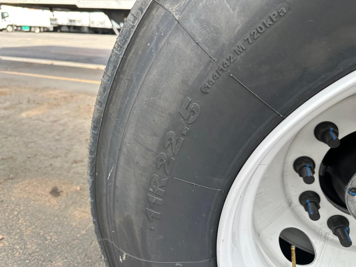 Tire section detail of a 2026 Timpte frac sand hopper trailer showing tire’s sidewall with markings and a light reflection.