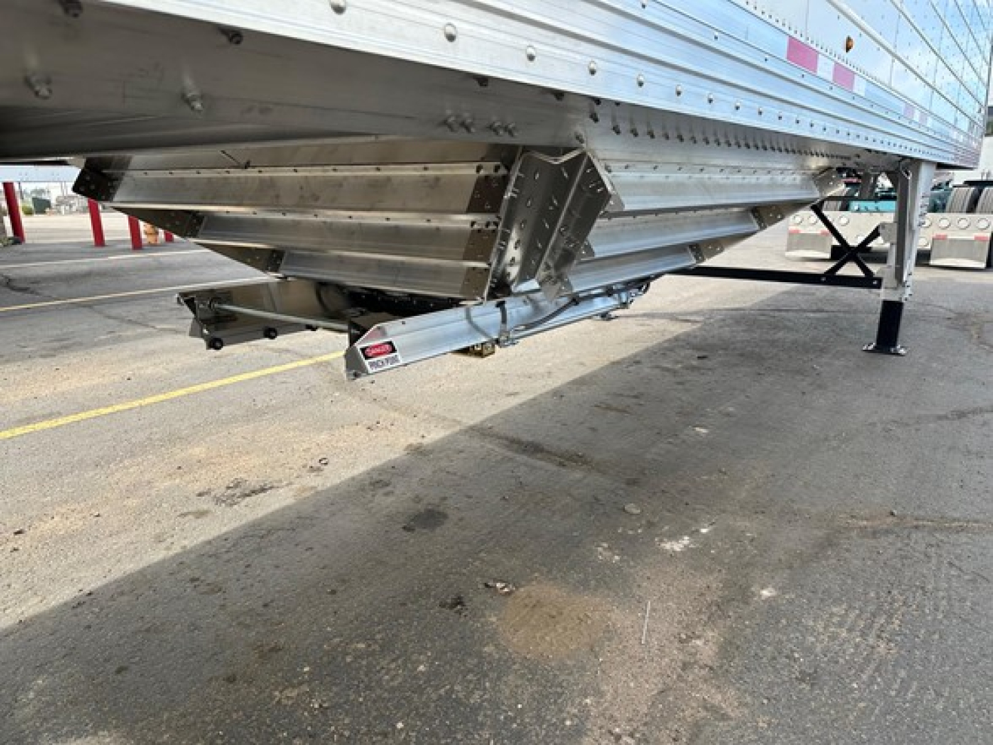 Framed underside view of a Timpte frac sand hopper trailer showing dual leg jack and silver structural components with a tank or auger system.