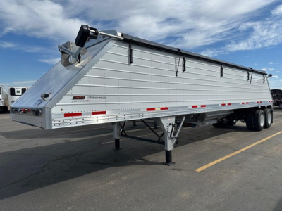 Timpte frac sand hopper trailer with side panels and dual rear wheels, silver metallic body, raised gooseneck, support legs visible.