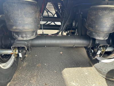 Fractured image of a Timpte frac sand hopper trailer undercarriage showing axles, suspension, and center axle housing with air springs and wiring.