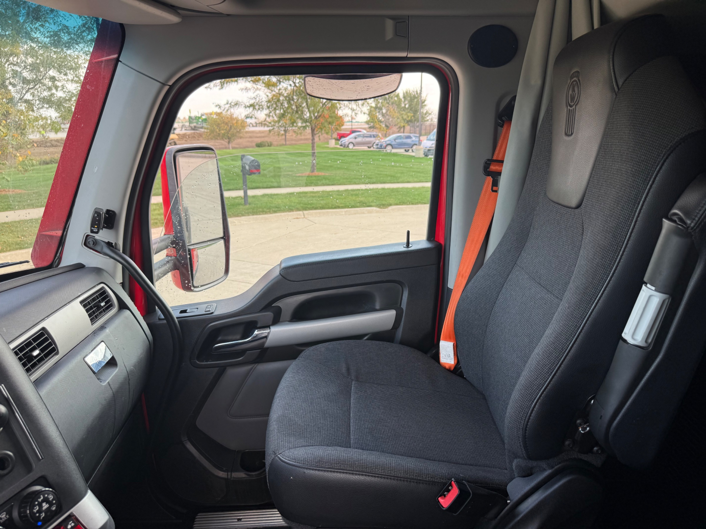 Kenworth T680 truck cabin interior showing front passenger seat, door panel, steering wheel, and window. Text not visible but part of the cab area.