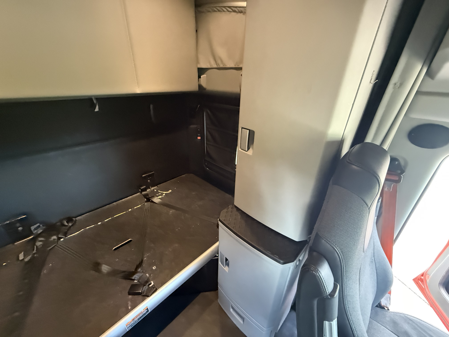 Kenworth truck cab interior showing sleeper area and doorway with seat visible. No legible model text or numbers readable in image.