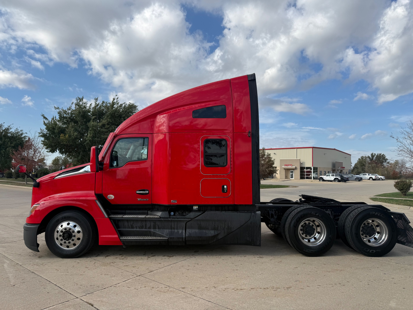 Kenworth T680 sleeper cab tractor in red showing side profile and tandem rear axles.
