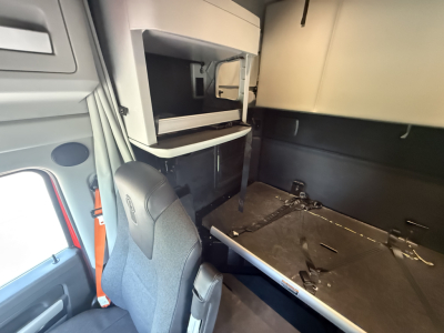 Kenworth T680 truck cab interior showing sleeper storage shelf and prep area with seat in foreground.