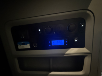Kenworth truck dashboard panel with blue digital display and control knobs, in-cab area visible.