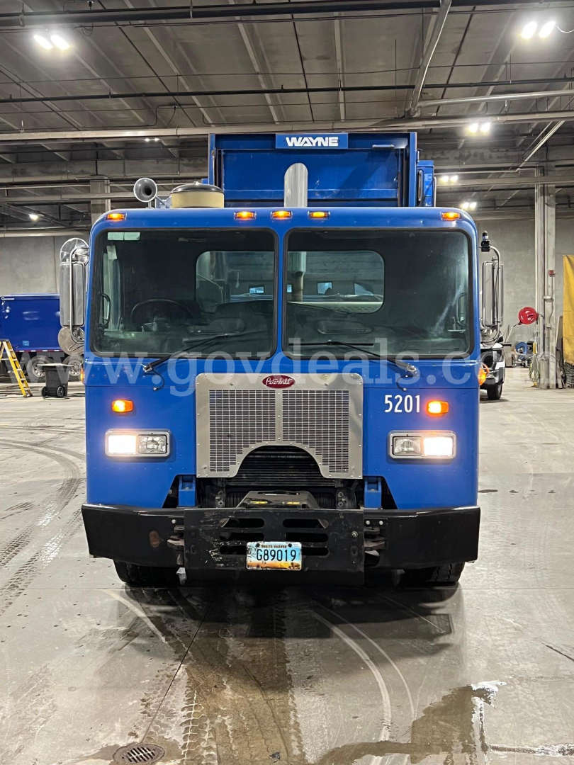 Peterbilt 320 truck in indoor facility with front grille, headlights, and crane attachment visible.