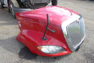 Front left fender of a red 2012 International Prostar truck with prominent grille, hood ornament, and side marker; text on side includes 'Volvo' sticker and handwritten notes.