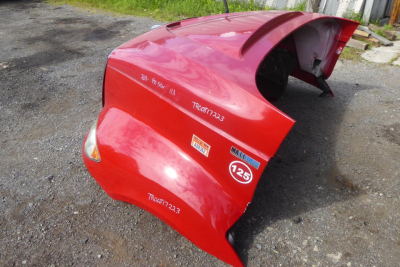 Red truck cab part with exposed hood and fenders, showing serial numbers and stickers including TRN07223 and 125 label.