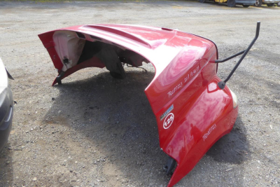 Truck cab front end cap pieces red with white diesel stickers and Trailers model numbers lying on gravel.