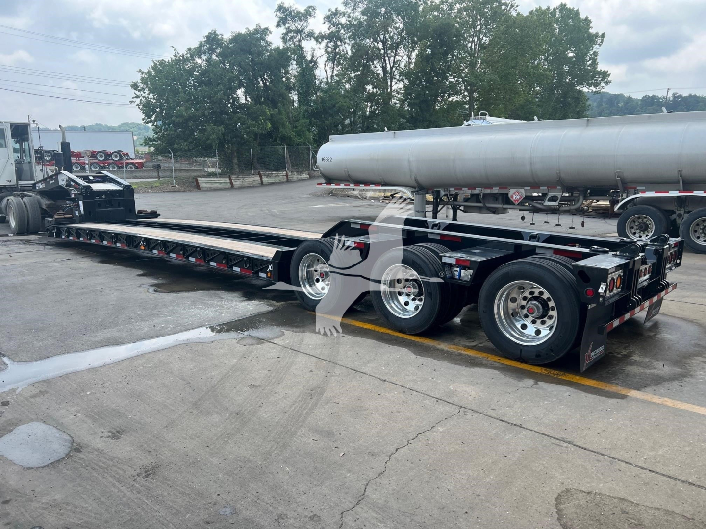 XL Specialized XL110HDGS lowboy trailer showing long flatbed and multiple axles with a large tanker on top.