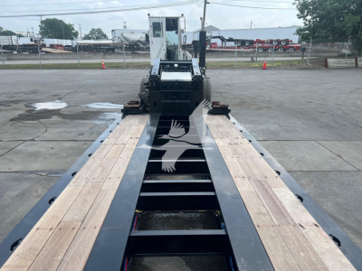 Trailer bed of a new XL Specialized XL110HDGS lowboy trailer showing wood deck sections and black steel frame with front gooseneck area.