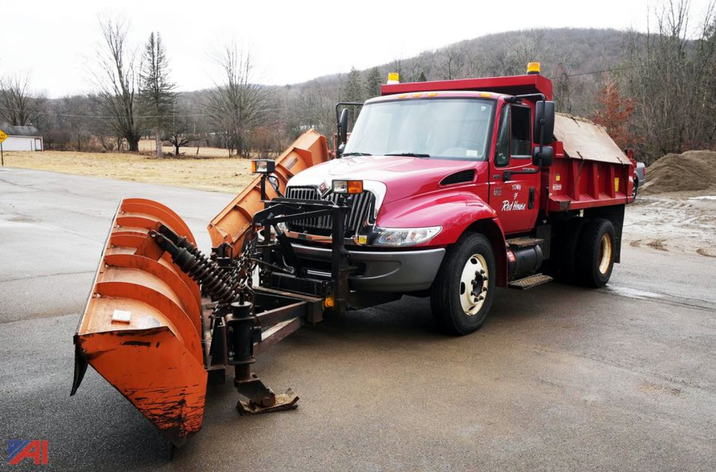 Dump truck with plow attachment in front, red International 4200, dump bed, plow and spreader visible.