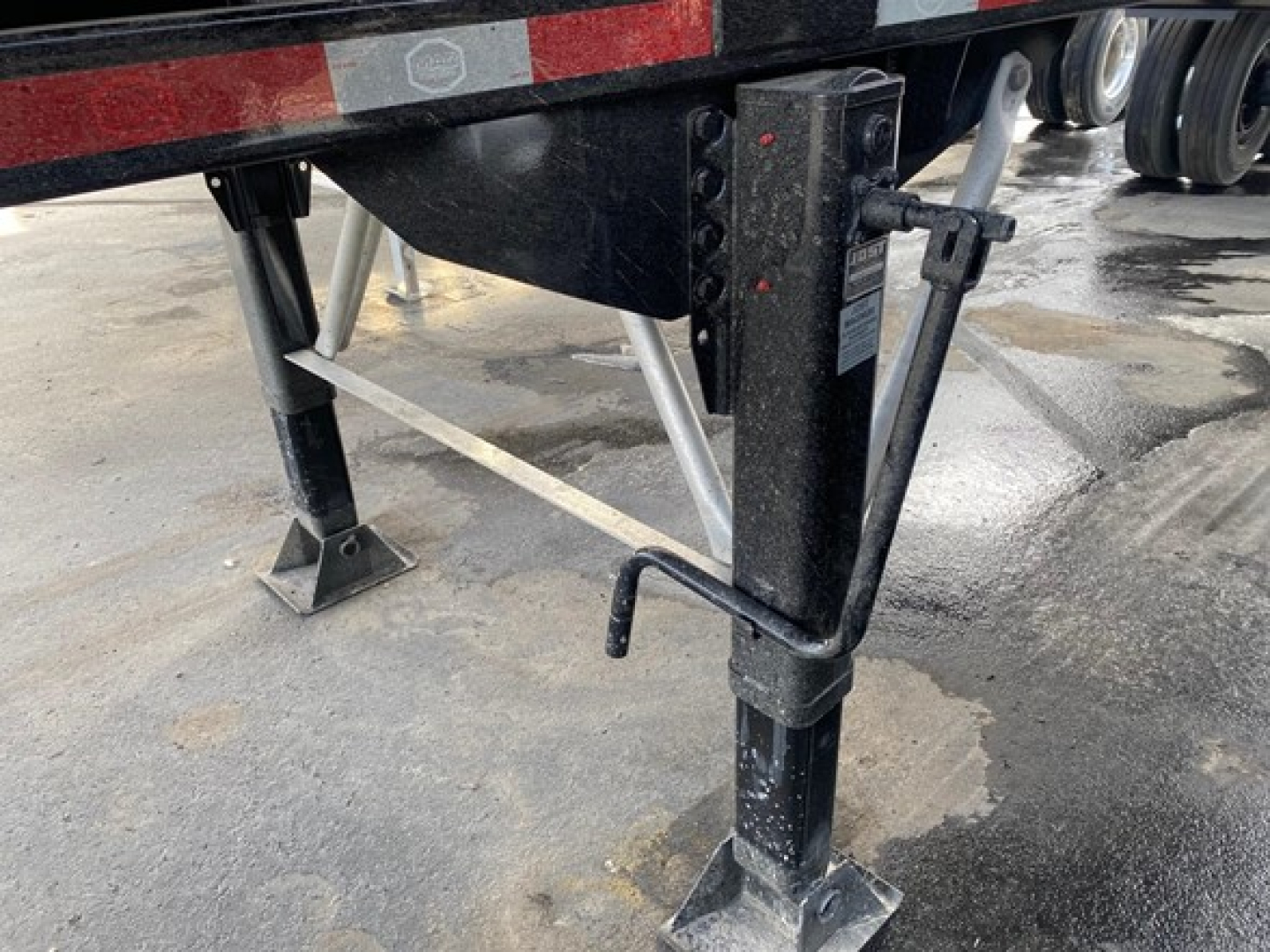 Trailer landing gear and underside with support legs and frame viewing a Mac High Cube 76" side scrap trailer.