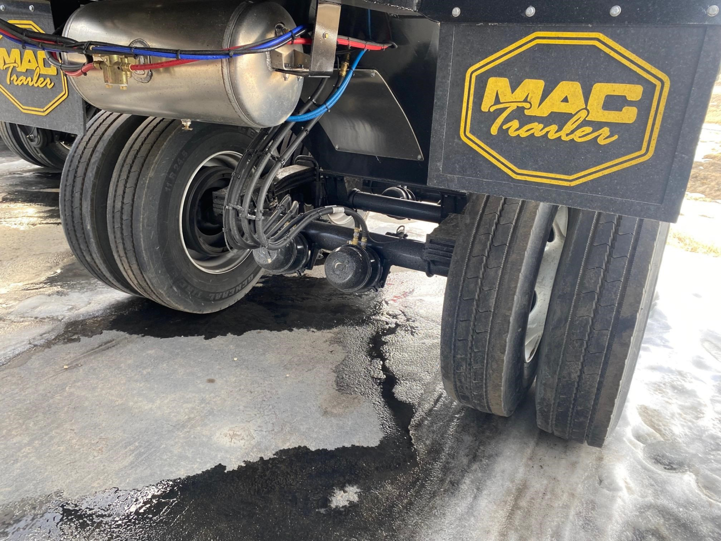 Mac Trailers view of rear underside showing dual rear wheels, suspension, and MAC Trailer branding plate on a new 2024 Mac High Cube 76 dump trailer.