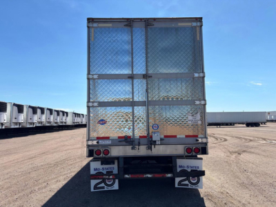Refrigerated trailer rear view with diamond plate doors and stock bumper, showing rear lights and mud flaps, utility reefer trailer in a lot.