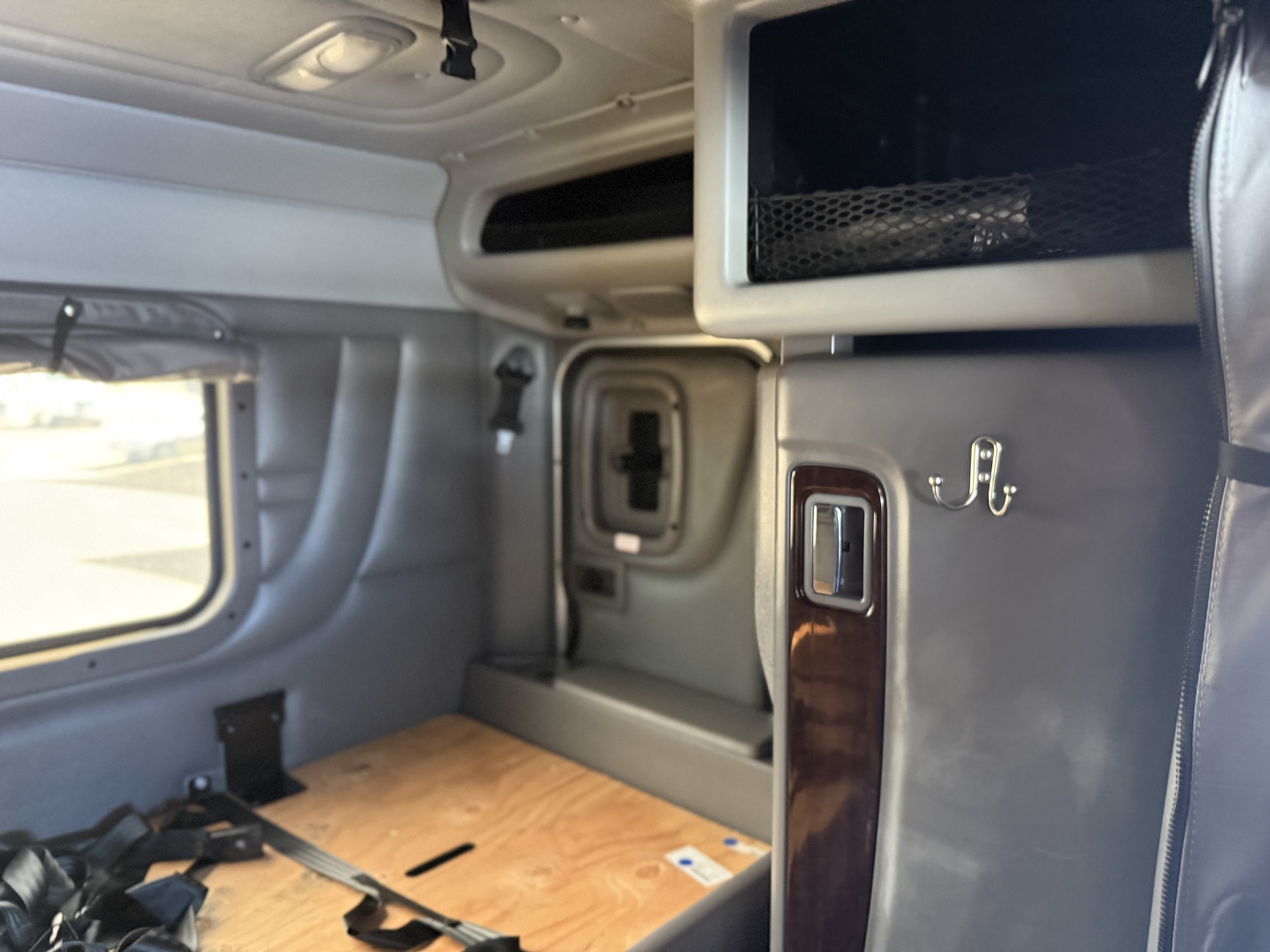 Truck cab interior of a 2019 Peterbilt 389 showing overhead storage, window, and partition with a small compartment; no dashboard text visible.