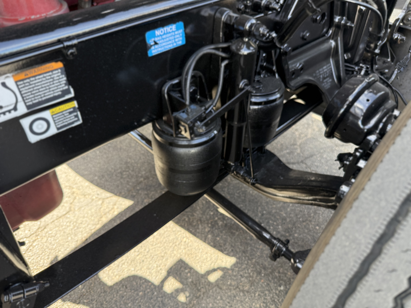 Peterbilt 389 chassis view showing air tanks and hydraulic lines under the cab, with VIN and stock stickers partially visible.