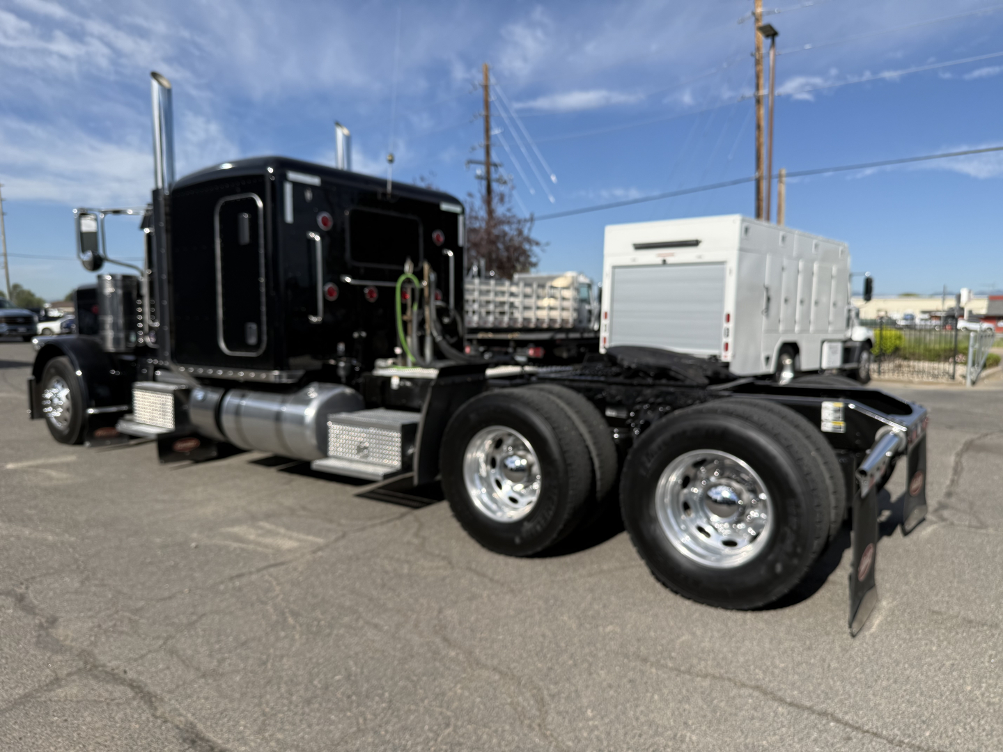 2019 Peterbilt 389 conventional sleeper truck with dual rear axles and chrome wheels, front cab black, side view showing fuel tanks and steps