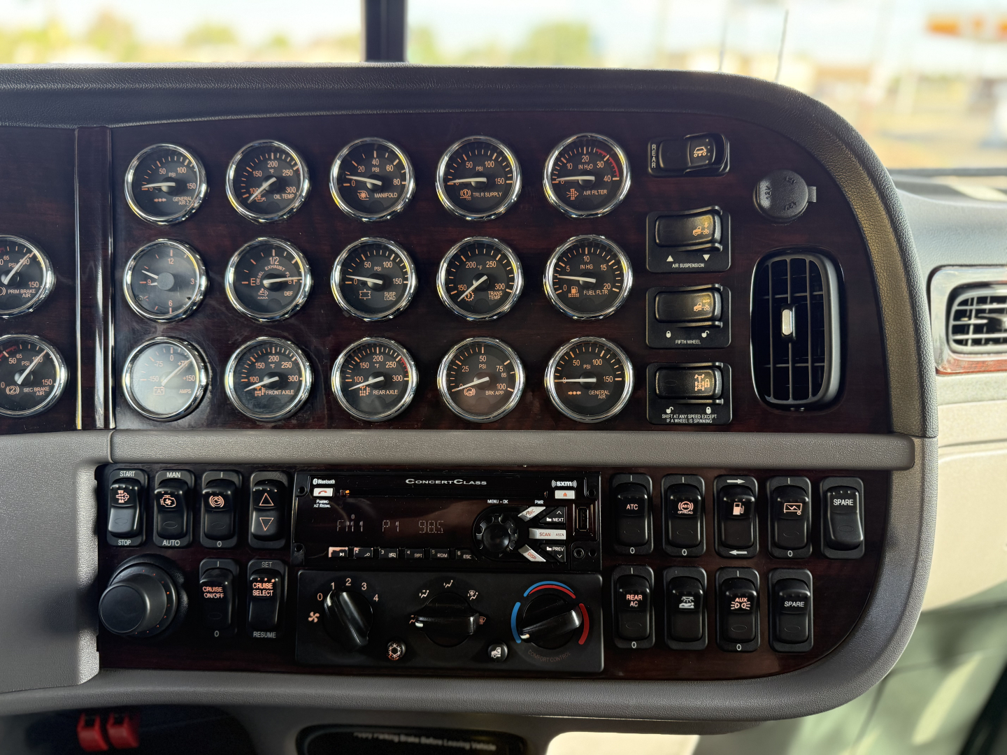 Peterbilt 389 gauge cluster and dashboard panels with numerous analog gauges and control switches in the cab.