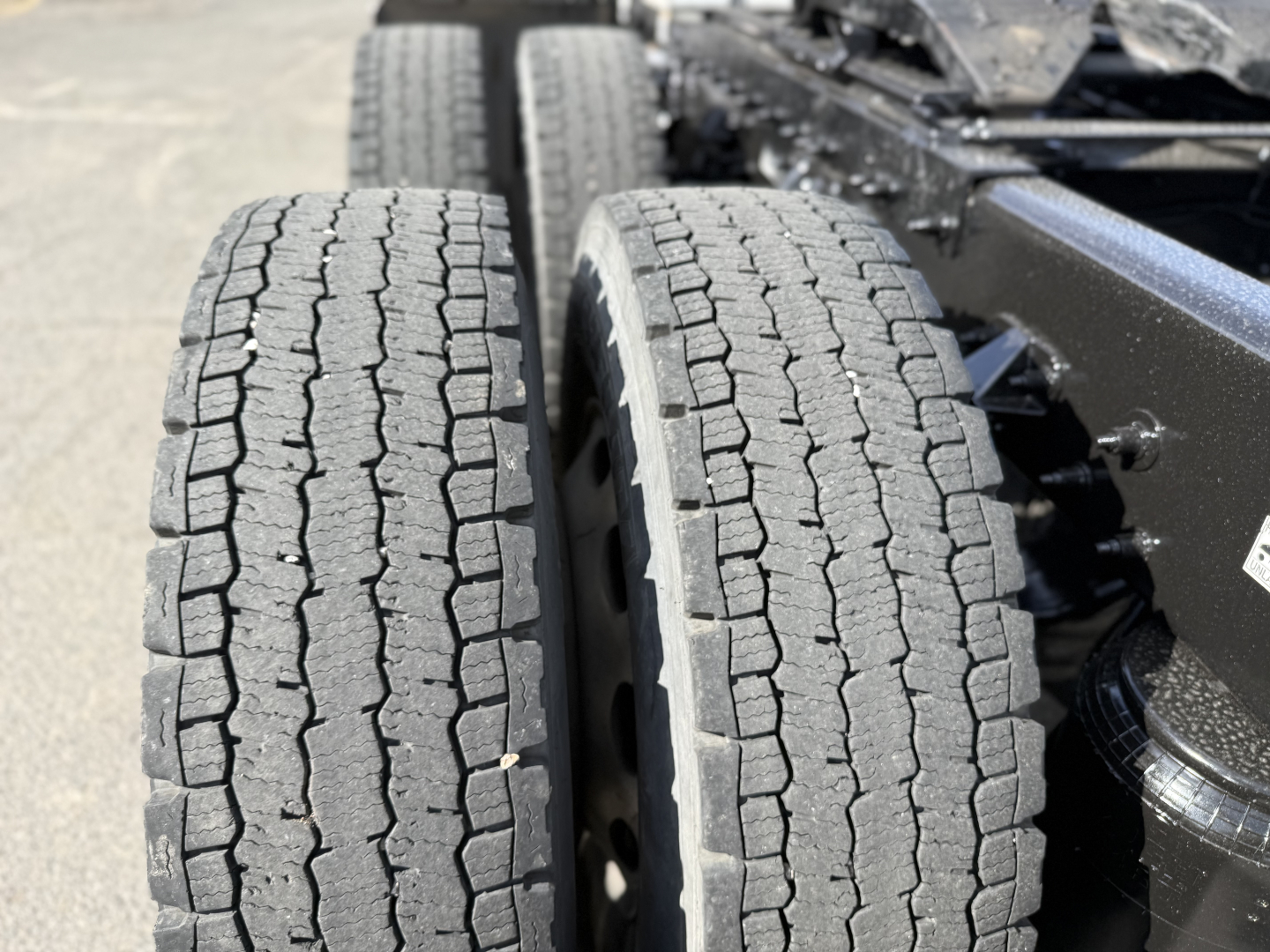 Peterbilt 389 truck rear showing dual rear axles with treaded tires and wheel rims.