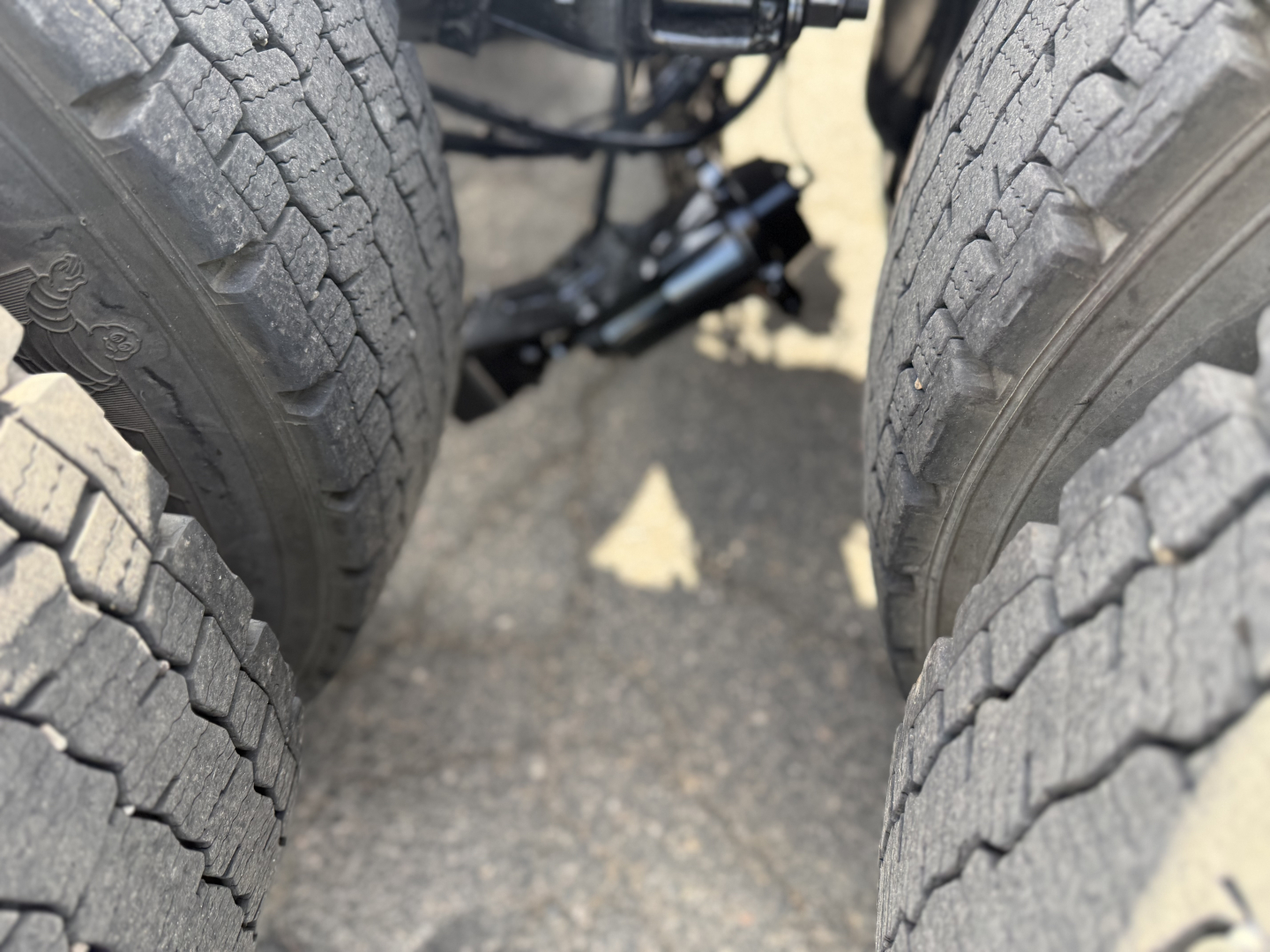Peterbilt 389 truck rear dual tires view showing suspension components and drive shaft area.